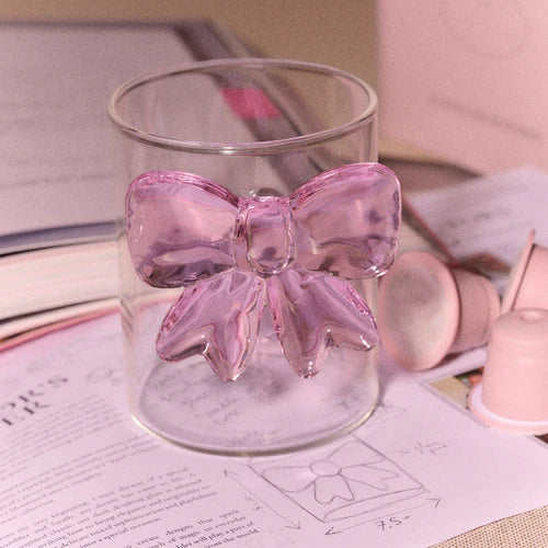 Verre transparent Lepelclub avec un grand nœud rose en verre sur une table